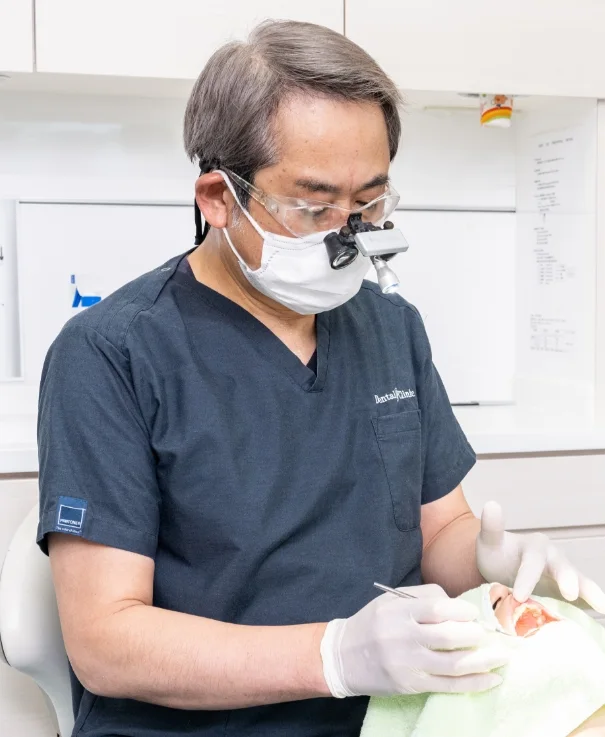 拡大鏡を使用して治療を行う院長